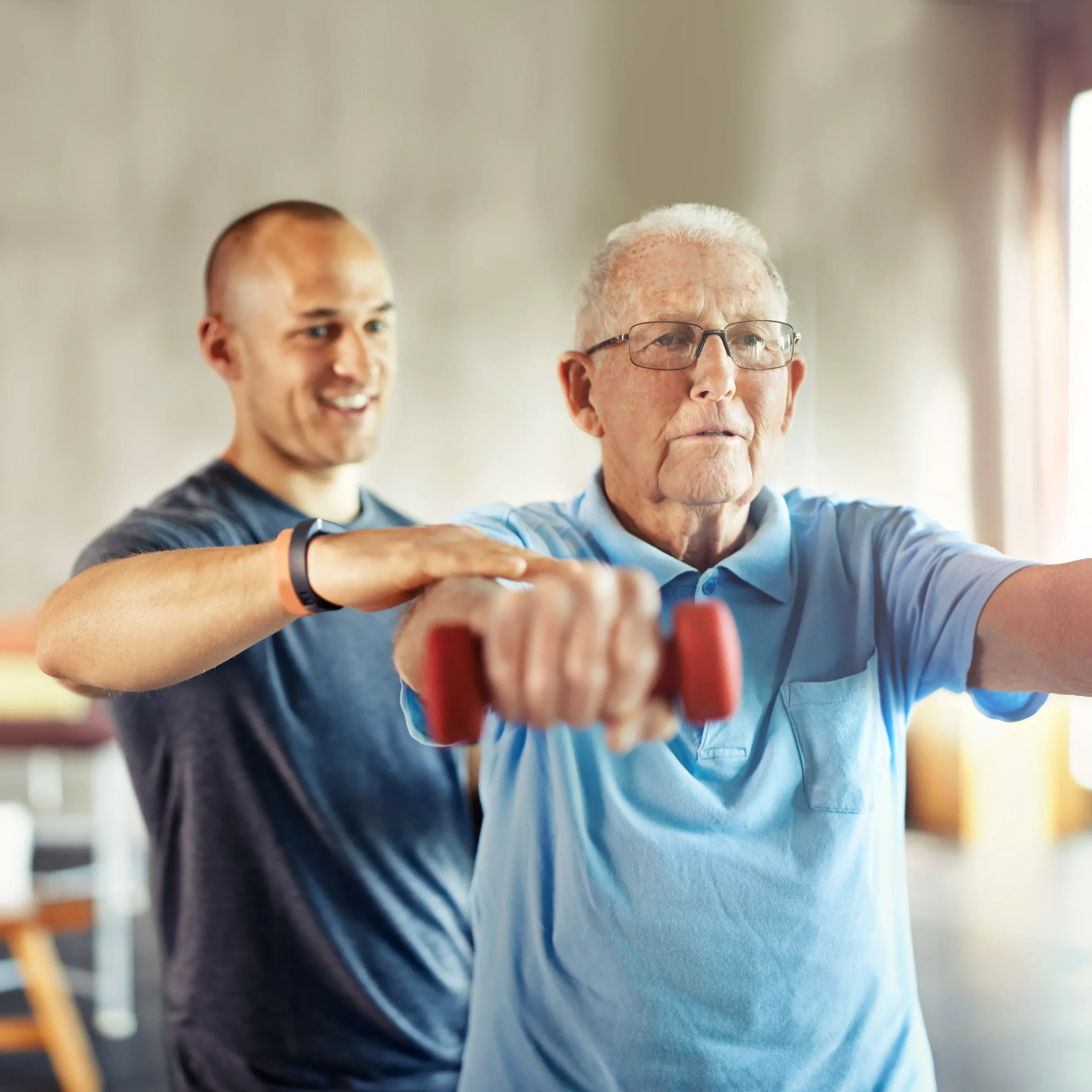 Two men, one younger, the Physical Therapist, and one older the patient, engaged in strength training with dumbbells, promoting health and physical therapy benefits.