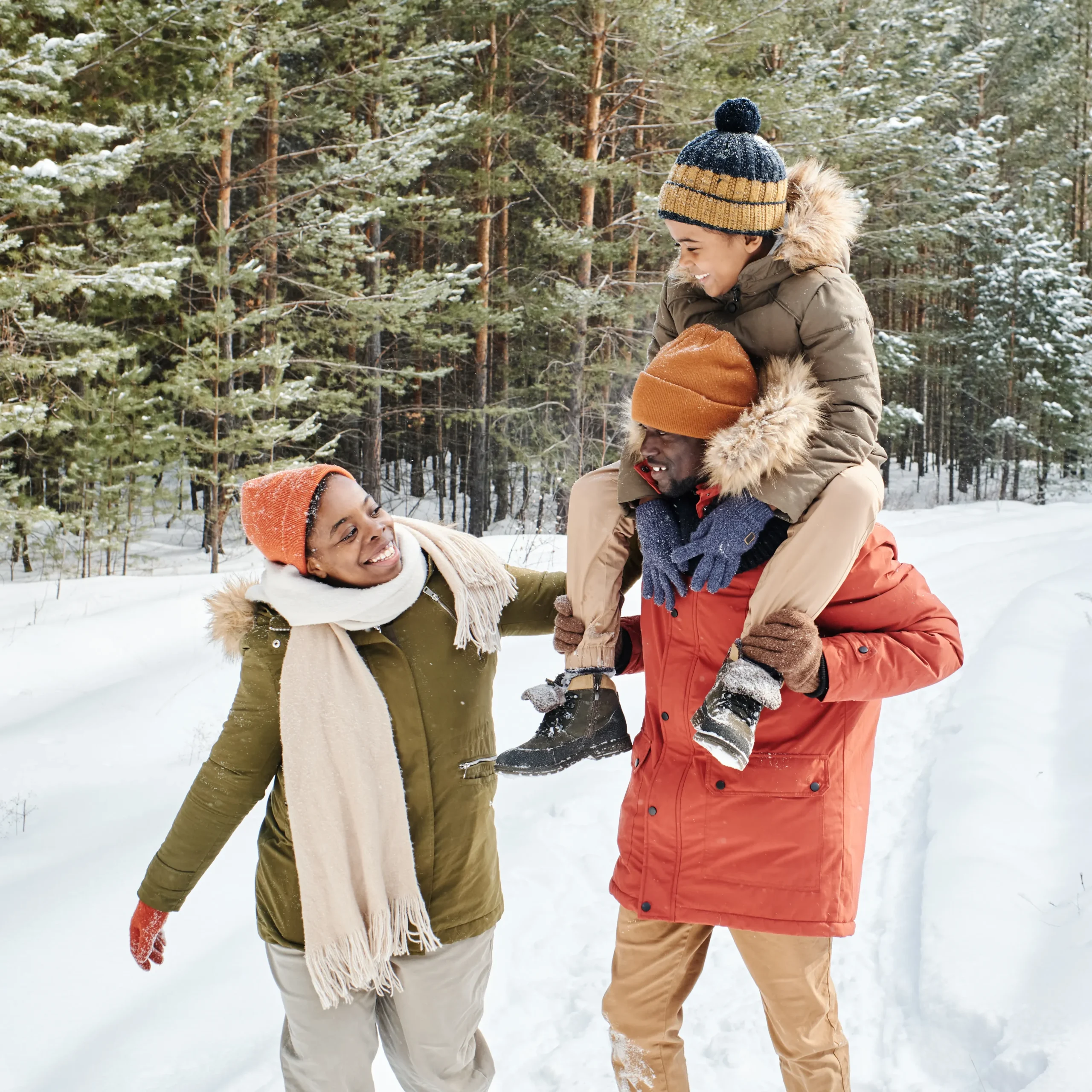 A family with child joyfully walking together in the snow, bundled up in winter clothing, enjoying the snowy landscape.