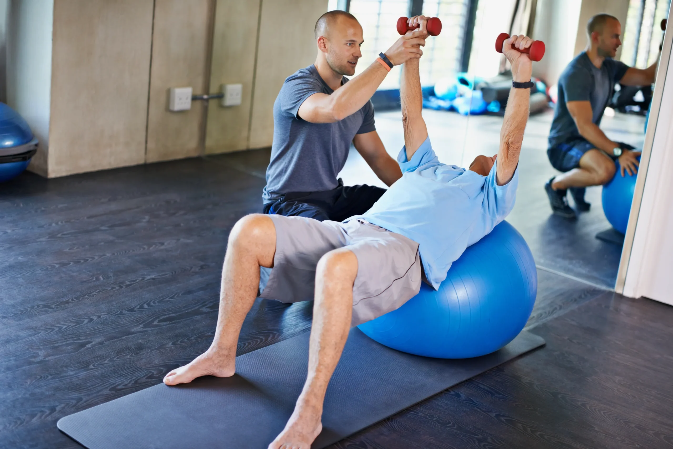 A man engages in strength and flexibility exercises using an exercise ball for balance and core stability.