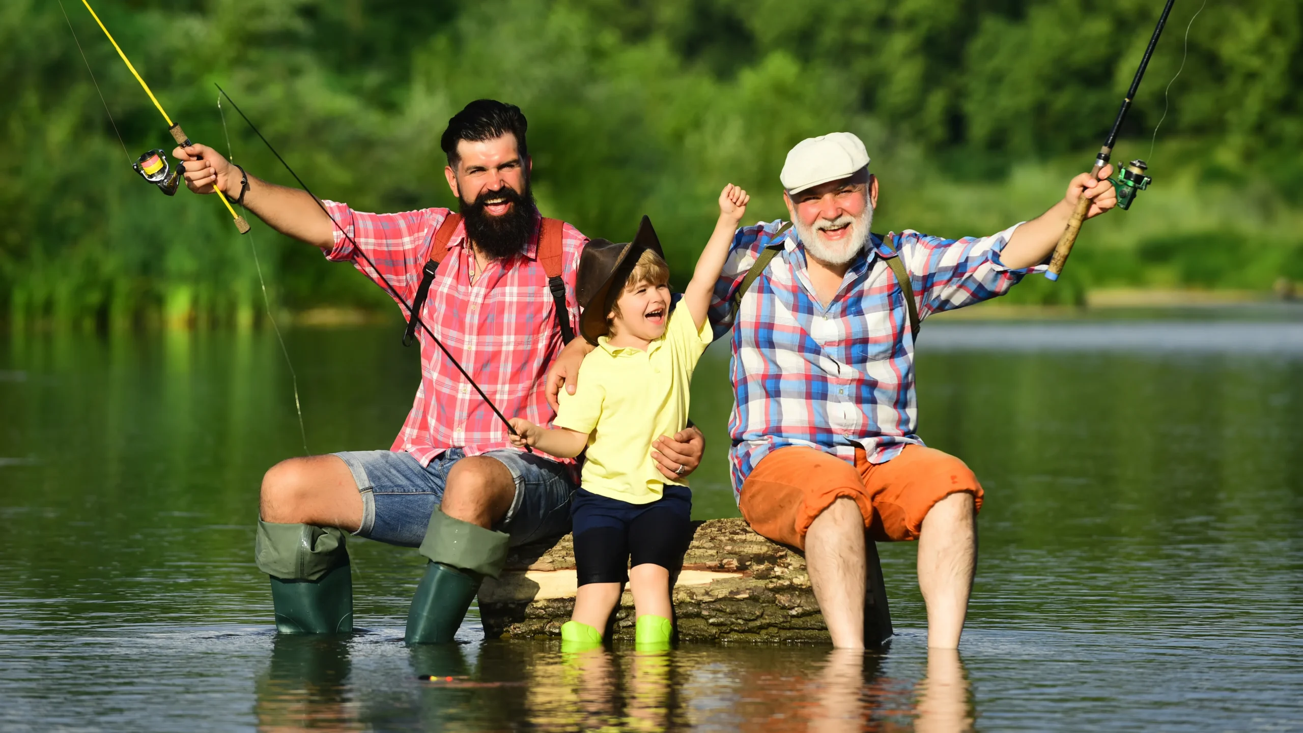 Two men and a child are fishing together at the water's edge, enjoying a sunny day outdoors.