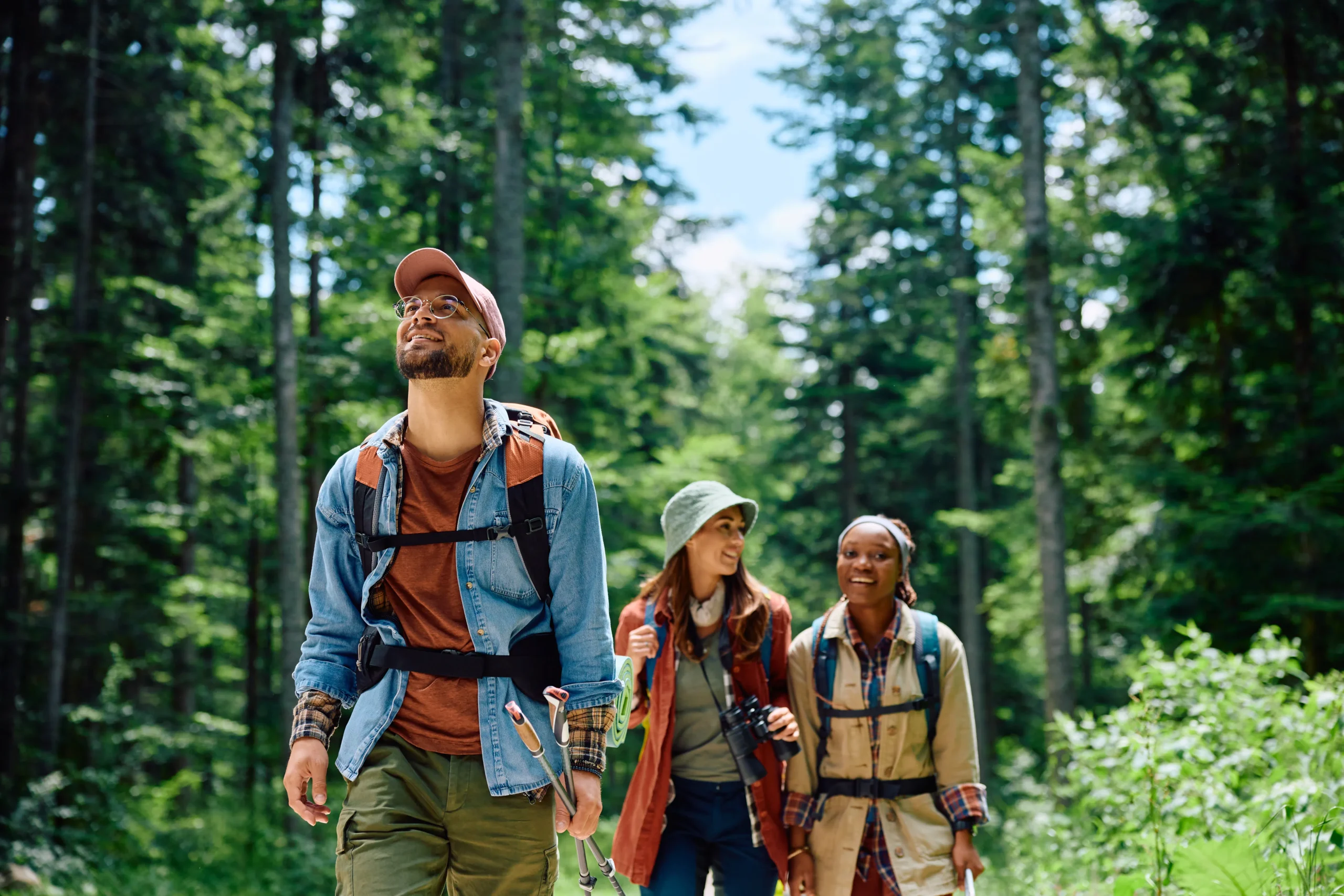 Three people with backpacks walking through a lush green forest, promoting outdoor activity and joint health awareness.