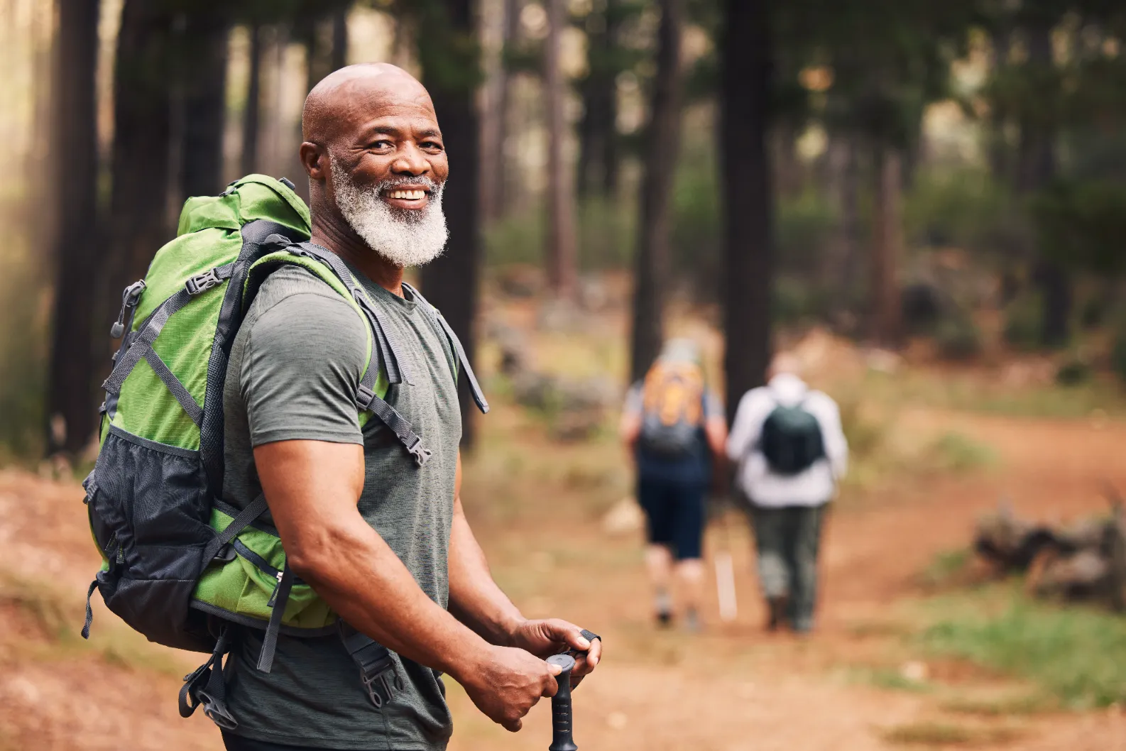Senior man hiking in forest, smiling