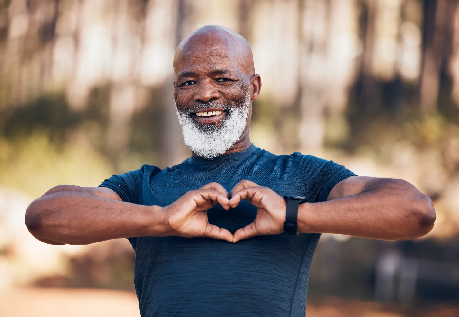 Black man hiking in forest, smiling with heart hand sign